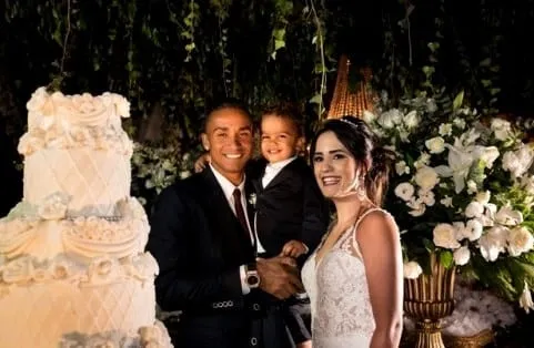 Love Towering High: The newlyweds, their son Miguel, and a stoic Danilo stand proudly beside their monumental wedding cake.