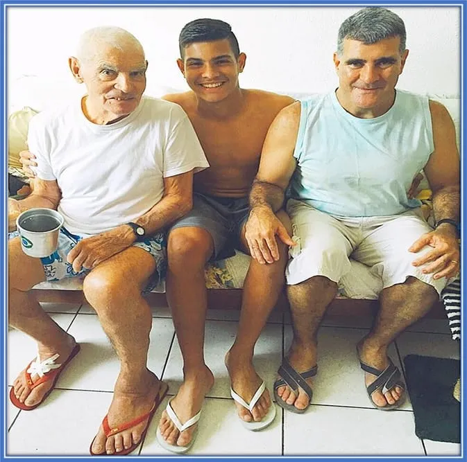 Young Bruno Guimaraes sitting in the middle of the two most important male figures in his life.