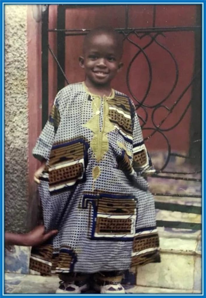 On this day, not many knew he would be a Premier League footballer. A smiling Doucouré takes a photo in front of his family home.