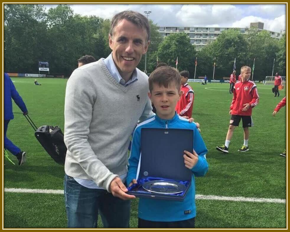 Phil Neville presents a young James McAtee with an award, celebrating the promising talent’s hard work and bright future ahead.