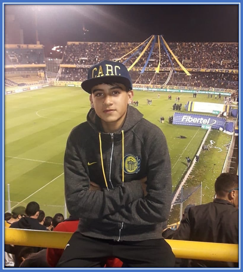 Facu, deep in thought, sitting in the iconic stands of Estadio Gigante de Arroyito, dreaming of following in the footsteps of football legends and making his mark on this historic stadium.