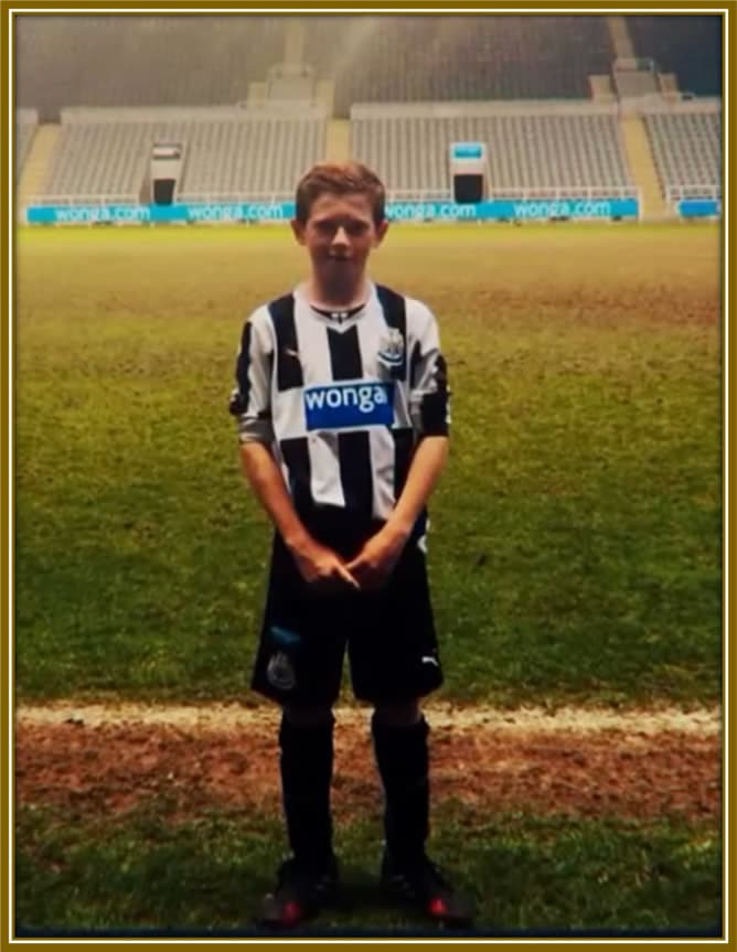 Young Elliot Anderson, just 9 years old, proudly standing on the field of St. James' Park in his Newcastle academy kit—a boy with big dreams and unshakable belief in his future. Credit: IG/elliotandersonn