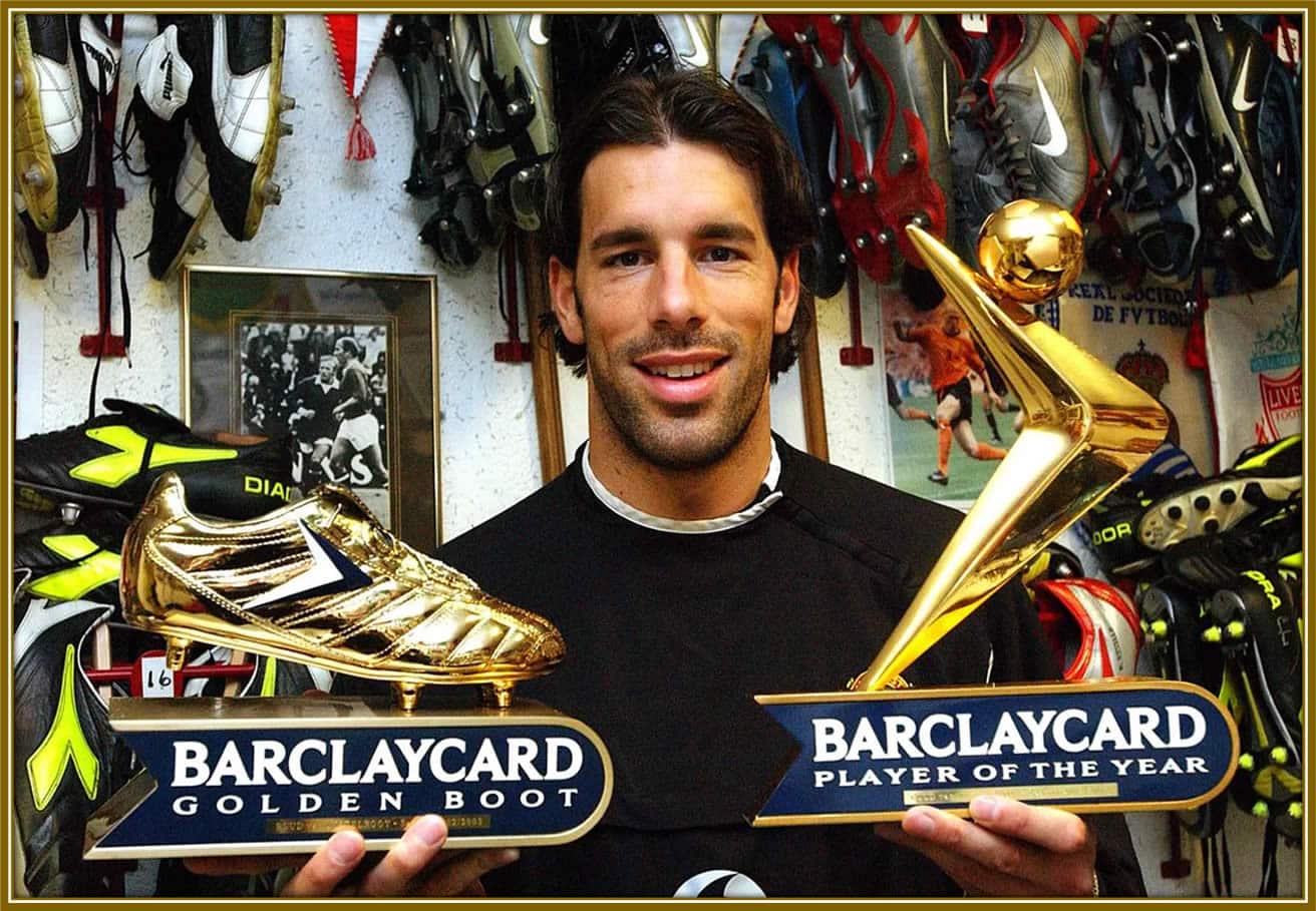 Ruud van Nistelrooy proudly smiling as he holds the Barclays Golden Boot and Player of the Year awards, celebrating his outstanding achievements on the field. Credit: ManchesterEveningNews