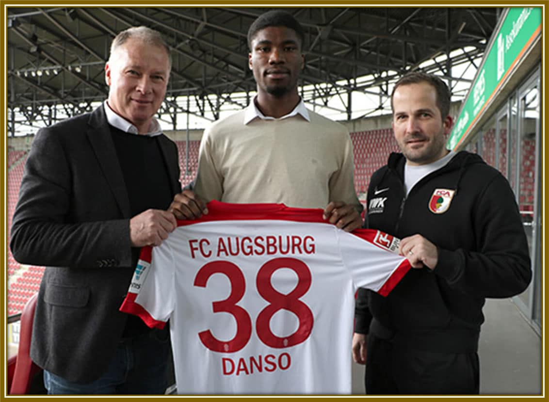 Young Kevin Danso proudly holds his FC Augsburg shirt, ready to embark on an exciting new chapter in his football journey.